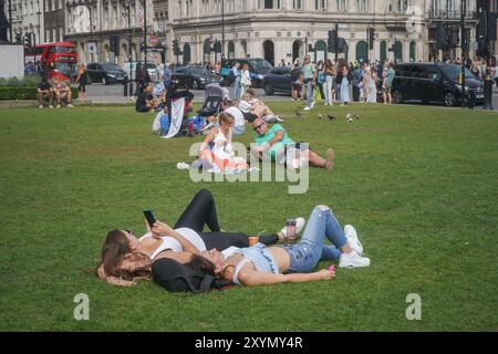 London. 30. August 2024. Touristen, die sich in der warmen Sommersonne am Parliament Square, London, entspannen. Das heiße Wetter wird sich bis September fortsetzen und die Temperaturen in London und Südosten Englands steigen. Quelle: Amer Ghazzal/Alamy Live News Stockfoto