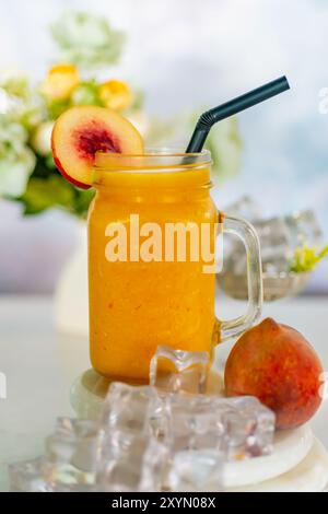 Erfrischender PfirsichSmoothie mit Eis und Blumen Stockfoto