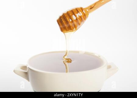 Saftiger Honig in einer Tasse und Löffel auf weißem Hintergrund Stockfoto