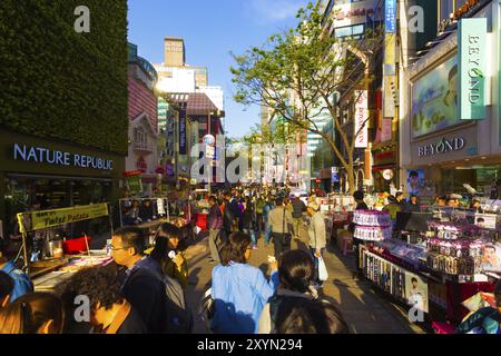 Seoul, Südkorea, 17. April 2015: Touristen gehen die enge Myeongdong Fußgängerzone entlang, mit Kommerzialisierung von Geschäften, Schildern und überfüllten Geschäften Stockfoto