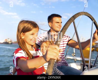 Junger Vater mit entzückenden Töchter ruht auf einem großen Boot Stockfoto