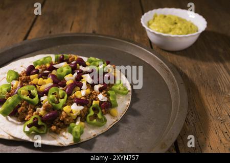 Mexikanische Tortillas mit Fleisch, rote Bohnen, jalapeno Pfeffer und Salsa Guacamole über einer Schüssel Stockfoto