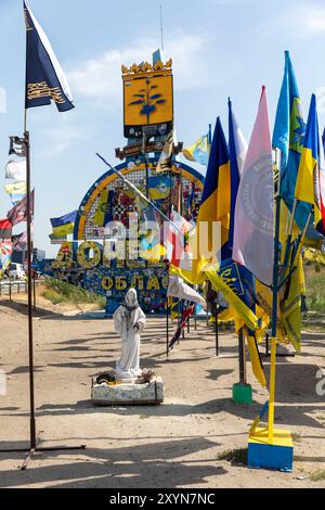 DONEZK Reg, UKRAINE - 29. August 2024: Statue der Jungfrau Maria und Flaggen der Brigaden, die das Donezk-Gebiet in der Nähe der Stele am Eingang zum Donezk-Gebiet verteidigen Stockfoto