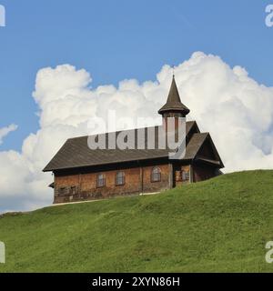 Himmlische Szene, alte Holzkapelle auf einem grünen Hügel, wunderschöne Wolken Stockfoto