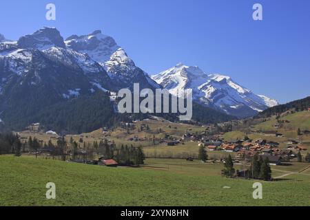 Dorf Gsteig bei Gstaad im Frühling. Grüne Wiese und schneebedeckte Berge Schlauchhorn und Oldenhorn. Landschaft im Berner Oberland, Schweiz Stockfoto