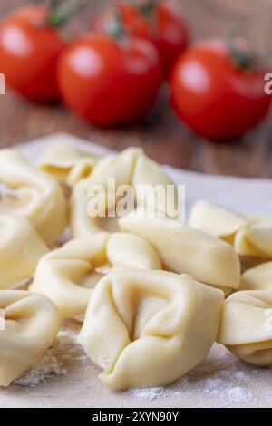 Rohe Tortellini auf Holz mit Tomaten Stockfoto