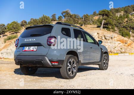 Kalkan, Türkei - 13. August 2024: 2024 Dacia Duster Rückseite. Modernes graues Geländefahrzeug steht am Straßenrand in der Nähe der Bergstraße auf einer sonnigen Summe Stockfoto