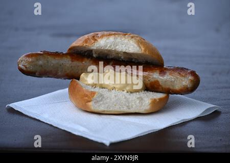 Erfurt, Deutschland. August 2024. Eine Thüringer Rostbratwurst mit Senf im Brötchen liegt auf einem Tisch. Der Name Thüringer Rostbratwurst ist seit 2004 als geschützte geografische Angabe eingetragen. Quelle: Martin Schutt/dpa/Alamy Live News Stockfoto