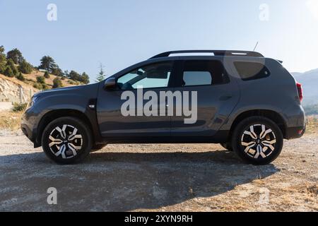 Kalkan, Türkei - 13. August 2024: 2024 Dacia Duster Seitenansicht. Modernes graues Geländefahrzeug steht am Straßenrand in der Nähe der Bergstraße auf einer sonnigen Summe Stockfoto