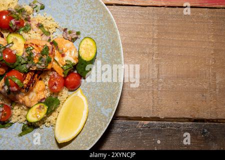 Ein köstlicher Teller mit Frühlingslachs und Garnelen Spieße mit Couscous Salat und Zitrussalsa auf einem Holzküchentisch Stockfoto