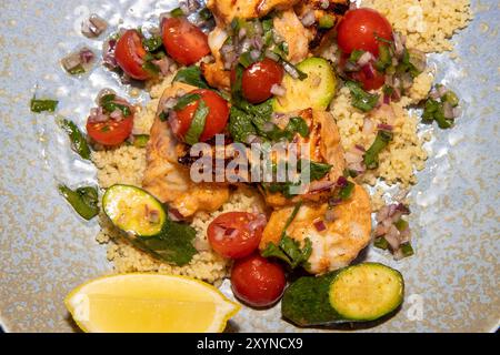 Ein köstlicher Teller mit Frühlingslachs und Garnelen Spieße mit Couscous Salat und Zitrusfrüchte Salsa Stockfoto