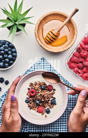 Gesundes Frühstück. Joghurt mit Müsli, Beeren, Früchten und Honig von oben Stockfoto