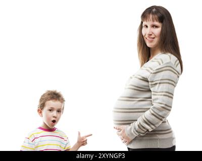 Wenig erstaunt oder überrascht Kind Jungen Zeigefinger zeigt seine schwangere Mutter Bauch weiß isoliert Stockfoto