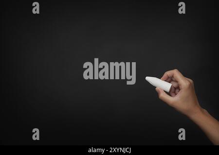 Hand mit weißem Stück Kreide über dunkler Tafel Stockfoto