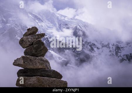 Cusco, Peru im Oktober 2015: Ein Felsstapel vor einem schneebedeckten Berg. Felsbrocken werden oft als Wegweiser für Bergwanderer verwendet Stockfoto