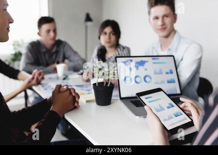 Geschäftsplanungstreffen, junge Kollegen oder Partner sitzen zusammen am Tisch im Konferenzraum mit Grafiken, Charts präsentiert von Manager, Disku Stockfoto