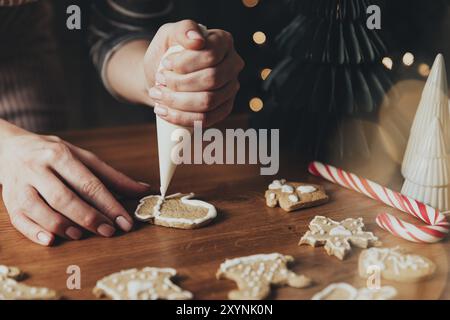 Weihnachten, Neujahrsvorbereitung. Weihnachten Lebkuchen Kochen, frisch gebackene Plätzchen zubereiten und dekorieren. Nahaufnahme mit Frauenhänden Stockfoto