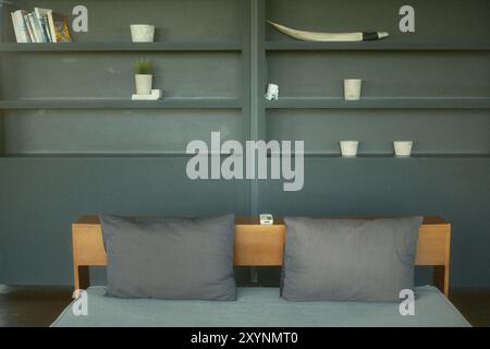 Tabanan, Bali, Indonesien - 26. August 2024: Gemütliches hölzernes Sofabett mit modernen schwarzen Regalen im Hintergrund Stockfoto