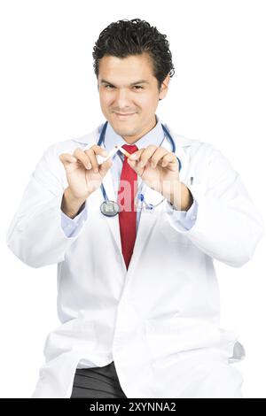 Ein gutaussehender latino-Arzt sitzt in der Hand einer kaputten Zigarette, ein Lächeln zeigt einen zufriedenen Ausdruck, der zeigt, wie wichtig es ist, das Rauchen aufzuhören Stockfoto