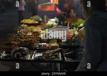 Fenghuang, China, 12. September 2007: Ein Straßenverkäufer, der auf einem Nachtmarkt in Asien eine Vielzahl von Spießen verkauft Stockfoto