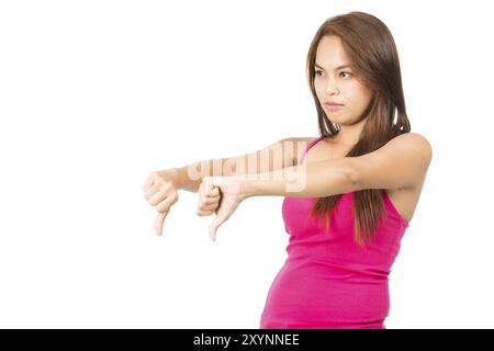 Profil einer schönen, runzelnden asiatischen Frau, die von der Kamera wegschaut, mit rosa ärmellosem Hemd, die wegschaut, mit zwei Daumen nach unten, um Missbilligung auszudrücken. Stockfoto