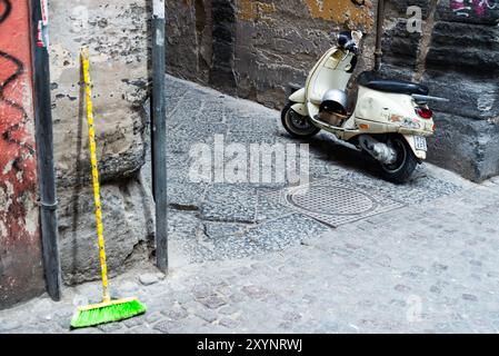 Sammlung aller Symbole, die mit Neapel verbunden sind - Graffiti, Roller und Besen auf einer kleinen schmalen Straße. Stockfoto