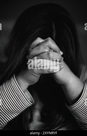 Nahaufnahme Porträt einer Frau mit gefalteten Händen vor ihrem Gesicht betend, christliches Konzept Stockfoto