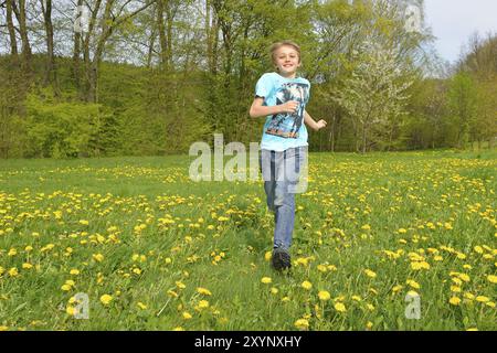 Der blonde Junge rennt über eine Wiese Stockfoto