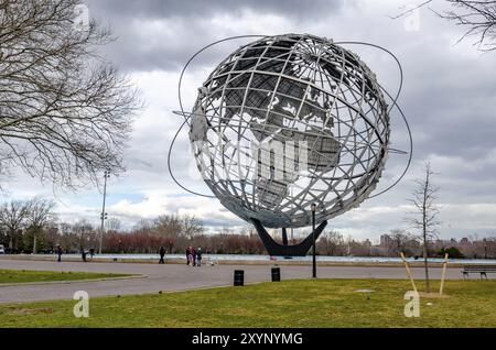 Unisphere im Flushing-Meadows-Park mit Wiese und Menschen, die vor dem Hotel stehen, Queens, New York City während des bewölkten Wintertages, horizontal Stockfoto