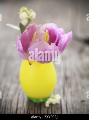 Osterkomposition mit Ei- und Pastell-Tulpenblüte und Maiglöckchen des Tales auf hölzernem Hintergrund. Nostalgische Innenausstattung. Farbige pi im rRtro-Stil Stockfoto