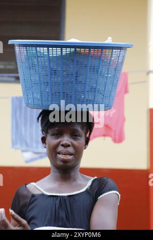 Eine junge Frau, die einen Wäschekorb auf dem Kopf trägt Stockfoto