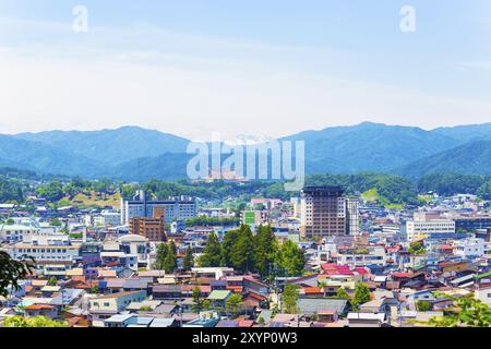 Takayama, Japan, 11. Juli 2015: Schneebedeckte Bergkette schwebte an einem sonnigen Sommertag hinter den Gebäuden der Innenstadt. Horizontal, Asien Stockfoto