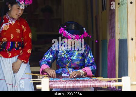 Lijiang, China, 2. Oktober 2017: Eine Naxi ethnische Minderheit, die in traditioneller Tracht gekleidet ist und Textilien mit einem Webstuhl in der Altstadt von Lijiang, Yunnan, webt. Stockfoto