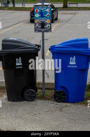 Toronto, Kanada, 08APR2024 - vertikale Aufnahme von Müll- und Recyclingbehältern neben dem Anweisungsschild auf einem öffentlichen Parkplatz Stockfoto