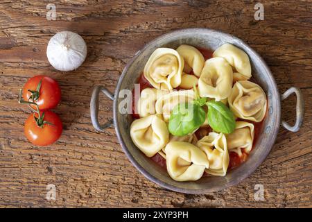 Tortellini auf Holz mit Tomatensauce Stockfoto