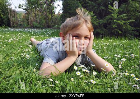 Blonder Junge, der auf einem Rasen liegt Stockfoto