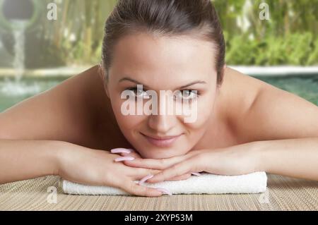 Junge Frau liegend in einem Spa bereit, um eine Massage in einem grünen Hintergrund Stockfoto