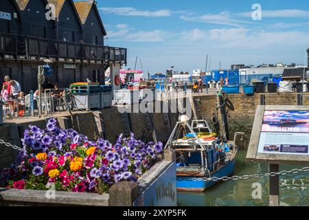 Whitstable, Großbritannien - 29. August 2024 Whitstable Hafen in Kent an einem sonnigen Sommertag bei Ebbe. Es gibt Fischerhütten und Fischerboote sowie Touristen und Stockfoto