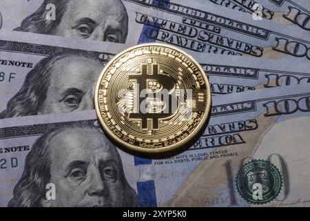 Ein Bitcoin auf hundert Dollar Rechnungen. Nahaufnahme, Makroaufnahme Stockfoto