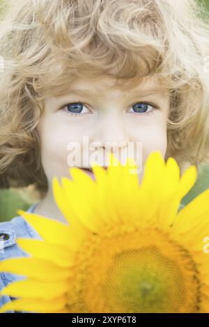 Porträt eines lächelnden Kindes mit Sonnenblume im Frühlingsfeld Stockfoto