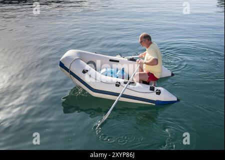 Mann rudert ein weißes Schlauchboot Stockfoto