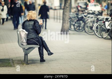 Ein Raucher sitzt allein auf einer Bank Stockfoto