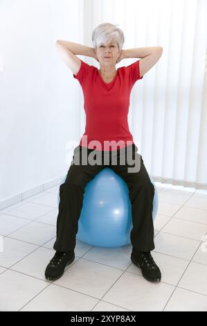 Frau, 50+, sitzt auf einem Trainingsball Stockfoto