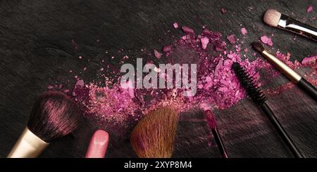 Ein Panorama aus Make-up-Pinseln und Lippenstift mit zerquetschter Kosmetik, von oben auf dunklem Hintergrund aufgenommen mit einem Platz für Text, einer Beauty Design-Templa Stockfoto