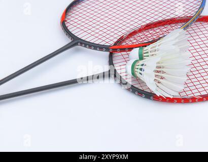 Weißer Shuttlecock aus Federn, die auf Badmintonschlägern vor weißem Hintergrund stehen und das Konzept der Bewegung für gute Gesundheit und darstellen Stockfoto