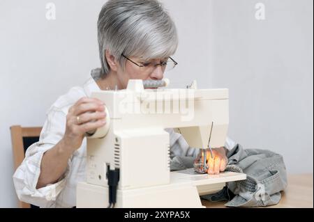 Frau, die an einer elektrischen Nähmaschine sitzt Stockfoto