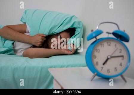 Teen Girl hasst es, früh morgens aufzuwachen. Schönes Mädchen, das sich schlecht fühlt, Menstruationsschmerzen hat und unter Kopfschmerzen, Emotionen und Stress leidet Stockfoto