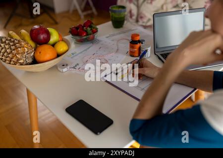 Ernährungsärztin, die wöchentliche Essensplanerin in ihrem Büro macht. Diät, gesunde Ernährung, Abnehmen und Gewichtsverlust Konzept. Stockfoto