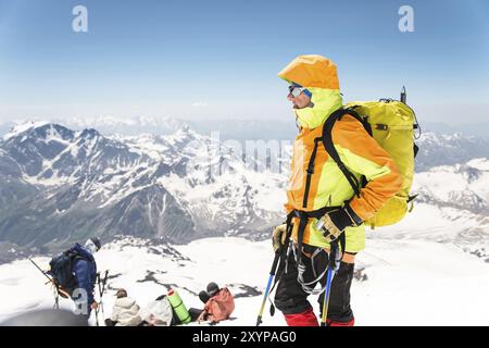 Ein Porträt eines Bergsteigers, der in professioneller Ausrüstung zum Bergsteigen vor der Kulisse anderer Bergsteiger und schneebedeckter Gipfel des Cauca gereift ist Stockfoto