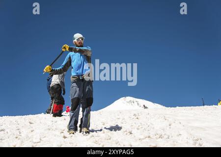 Training zum Korrigieren des Rutschens an Hanglagen oder Gletschern mit Hilfe einer Eispistole. Ein junger Reiseleiter mit Bart erklärt seiner Gruppe, wie man das richtig verlangsamt Stockfoto